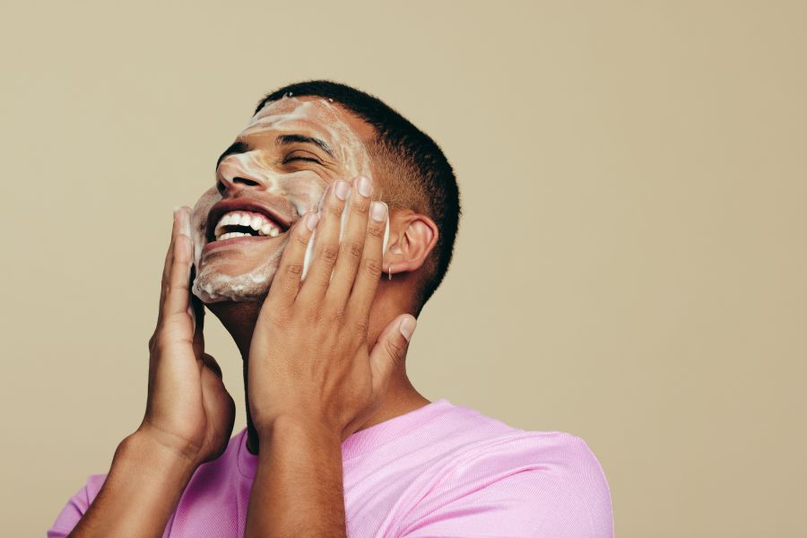 man putting cream on face smiling